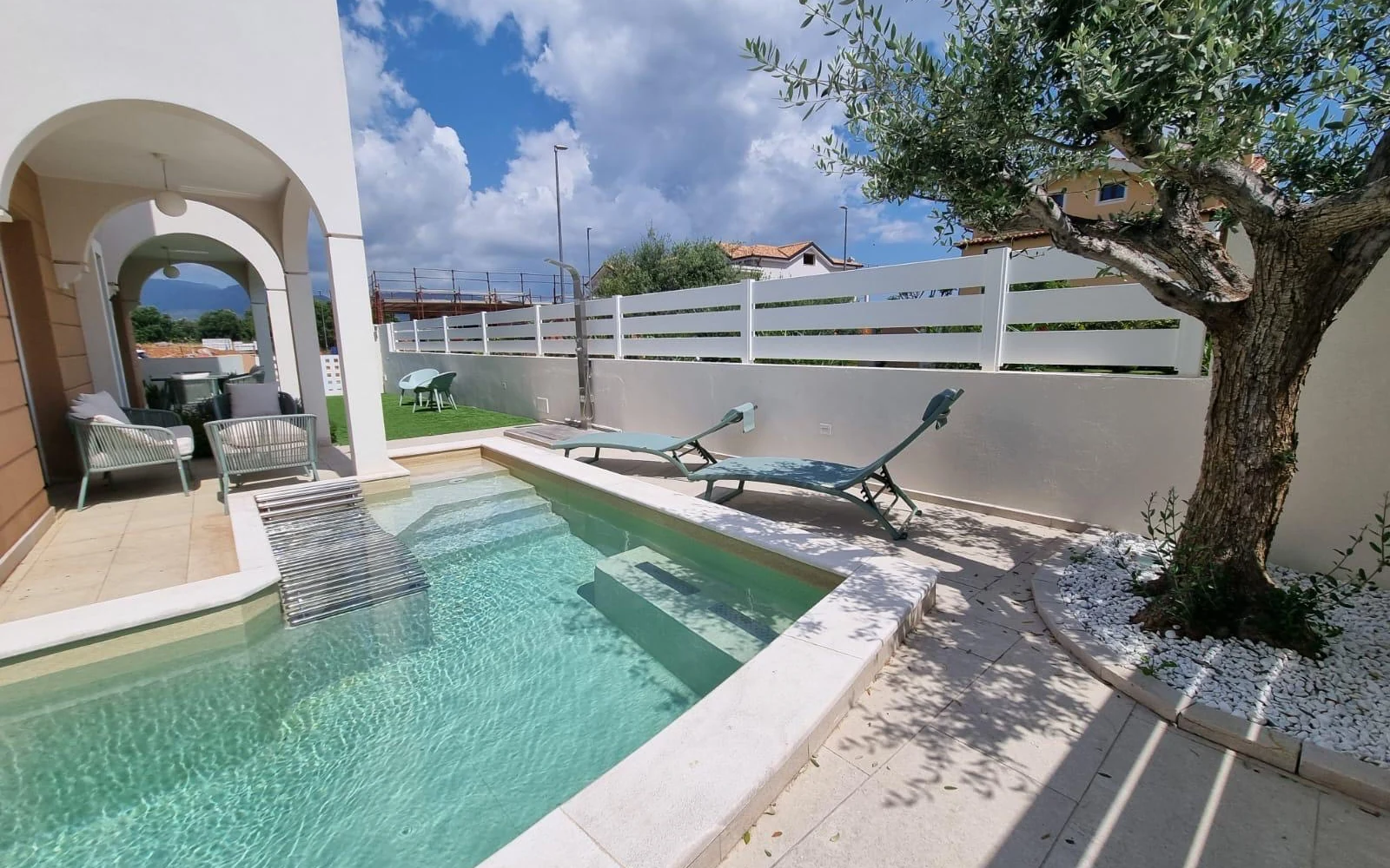La piscina privata della villa con l'ulivo e il portico