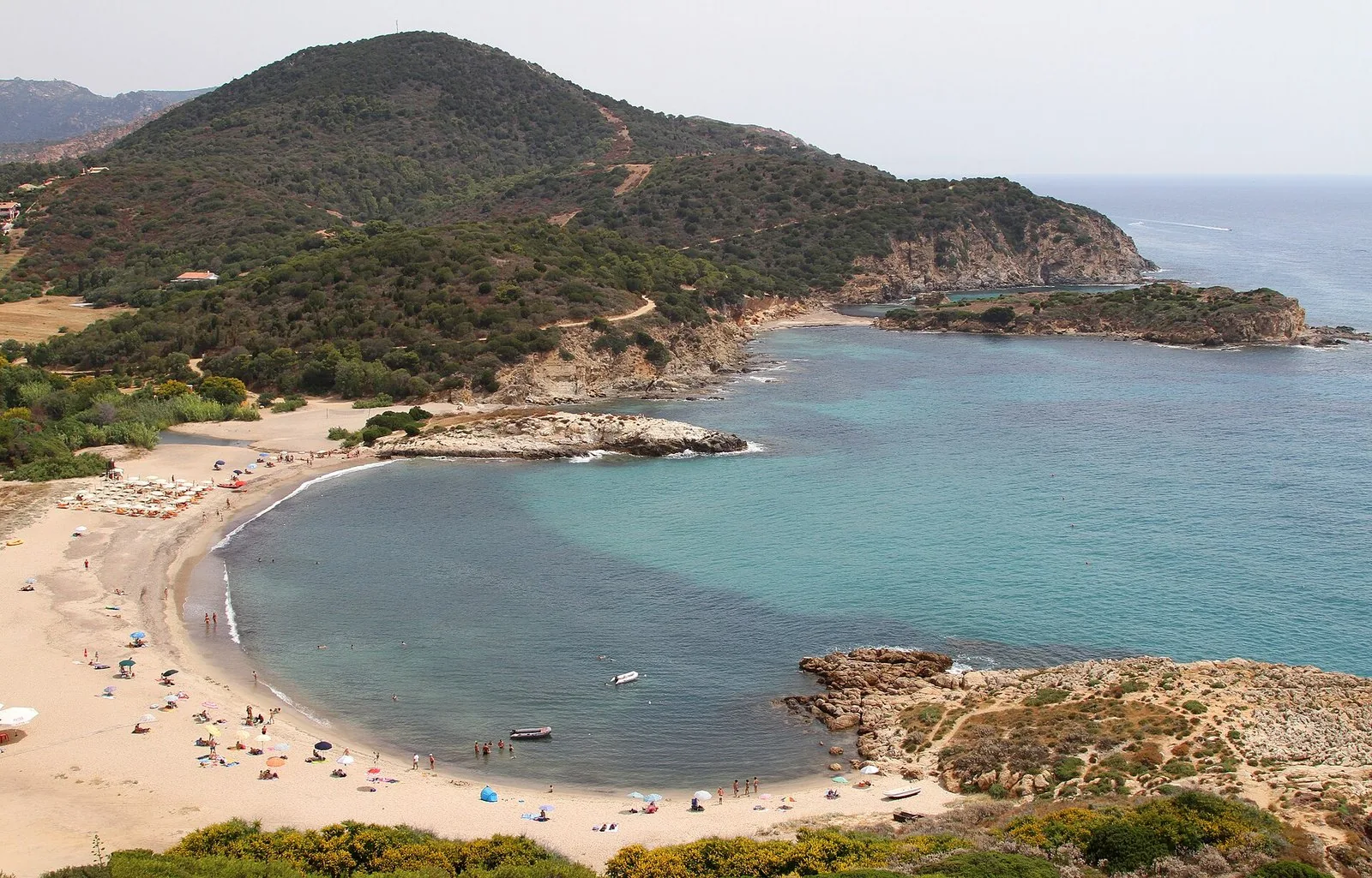 La baia di Chia vista dall’alto, con la torre sul promontorio e il mare turchese